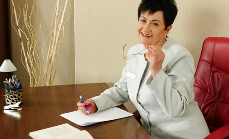 Curious older Karoline in skirt revealing big knockers and spreading her legs in office